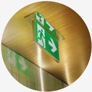 Slim exit sign with gold trim mounted to ceiling